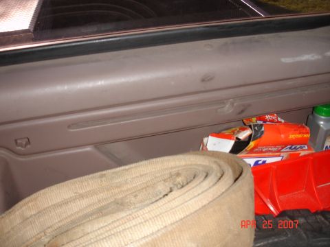 1995 Ford Bronco - A close-up view of a vehicle's interior storage compartment containing a rolled hose and various items.