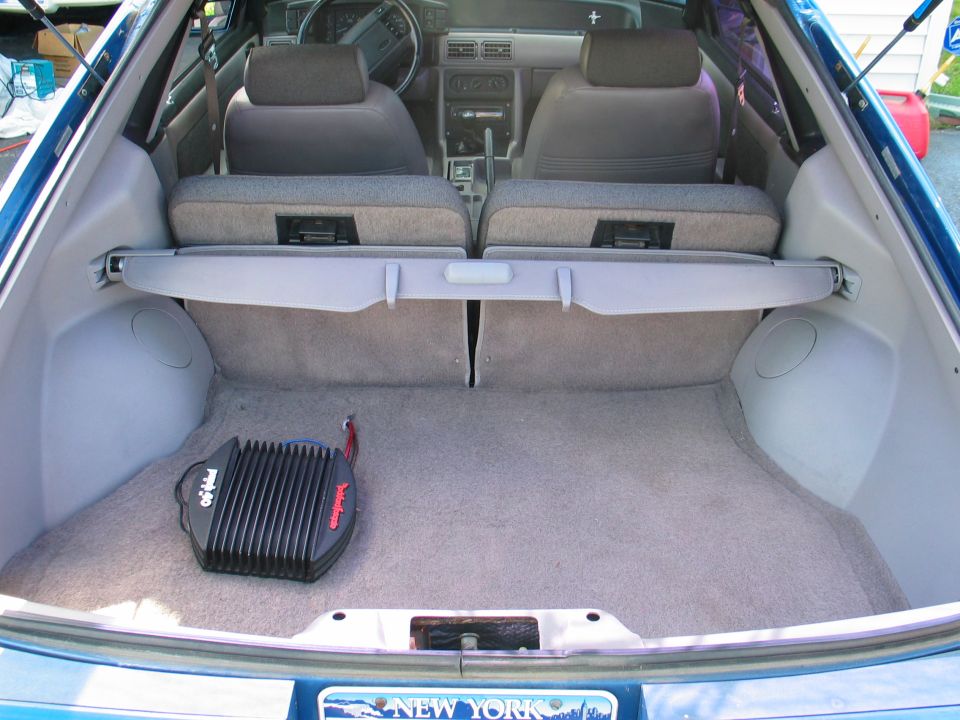 Gray hatchback rear cargo area with folded seats and an amplifier