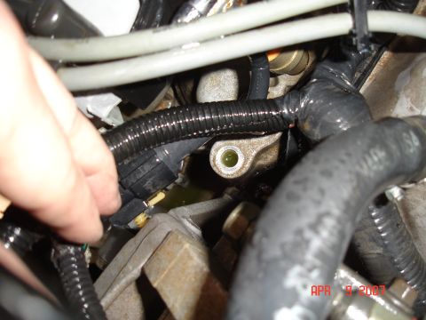 1995 Ford Bronco - Close-up of engine bay components, showing a hand interacting with a sensor.