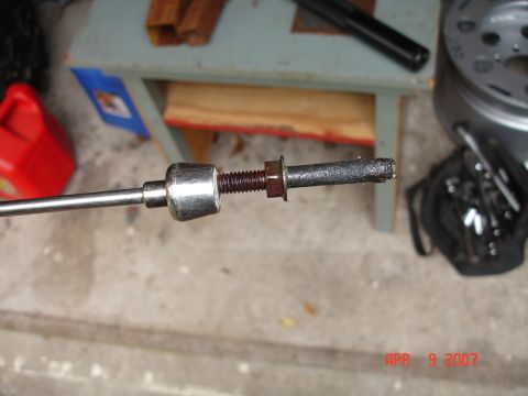 1995 Ford Bronco - Close-up of a worn metal cable end with a nut and bolt, against a concrete background.