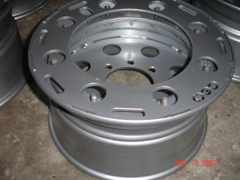 1995 Ford Bronco - A close-up view of a silver alloy wheel, likely a replacement part, with visible bolt holes and a textured surface.