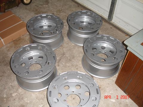 1995 Ford Bronco - A collection of five aluminum wheels are displayed on a concrete floor, possibly in a garage.