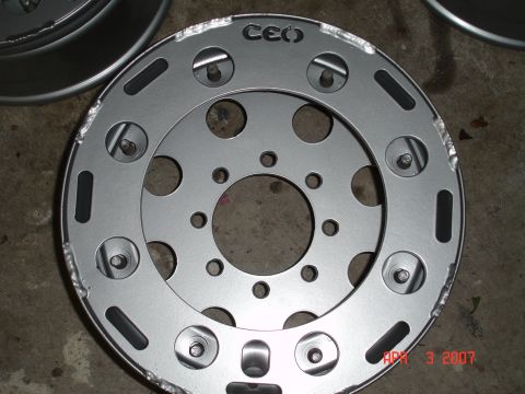 1995 Ford Bronco - A close-up view of a silver metal wheel rim with a distinctive 'CEO' logo and various circular cutouts.