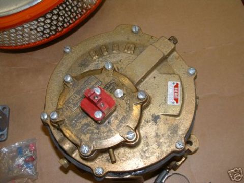 1978 Ford Bronco - A brass propane converter with a red cap is shown next to an air filter component. The registry claims it is from a 1978 Ford Bronco, but t…
