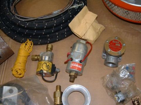 1978 Ford Bronco - A collection of automotive parts, including a fuel filter and various fittings, are laid out on a surface.