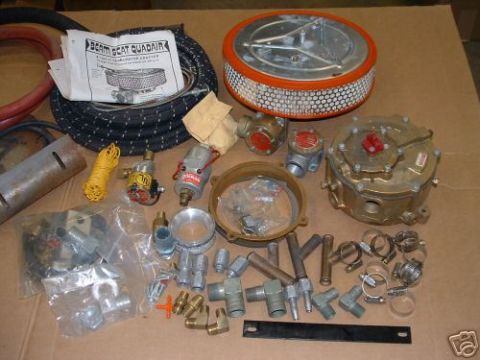 1978 Ford Bronco - A variety of automotive parts are laid out, including an air cleaner, hoses, regulators, and numerous fittings, suggesting a kit or invento…