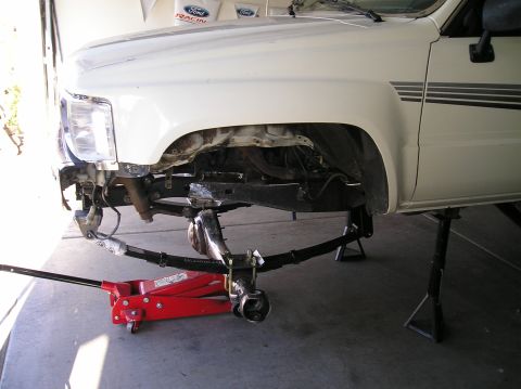 1986 Toyota Hilux - Front suspension of a white pickup truck, likely from the 1980s, is undergoing maintenance.
