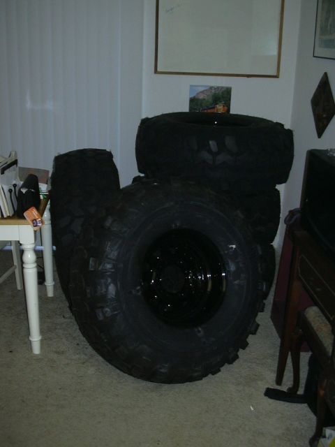 1995 Ford Bronco - A collection of large, knobby tires are stacked in a room, suggesting off-road vehicle modifications.