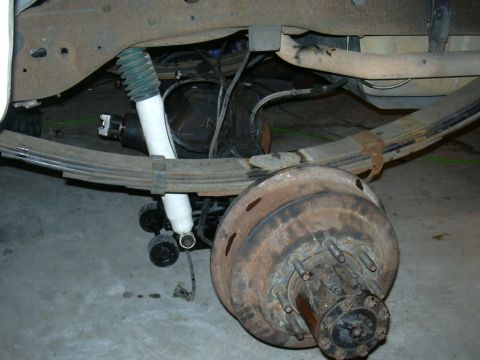 1995 Ford Bronco - Close-up view of the rear suspension and axle components of a vehicle, with visible rust and wear.