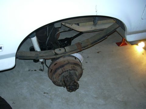 1995 Ford Bronco - The rear axle and leaf springs of a white 1995 Ford Bronco are visible, suggesting a solid axle swap modification.