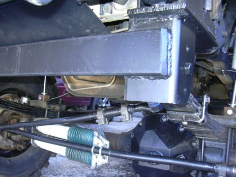 1995 Ford Bronco - Close-up of the undercarriage showing a solid axle swap with prominent green and white shock absorbers.