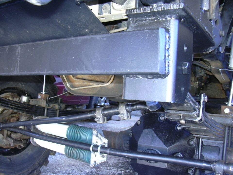 Undercarriage view of a solid axle swap with green and white shocks