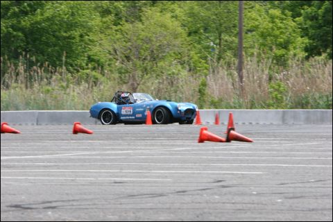 2001 Mercury Grand Marquis - A blue convertible sports car is seen on a race track, maneuvering around orange cones during an event.