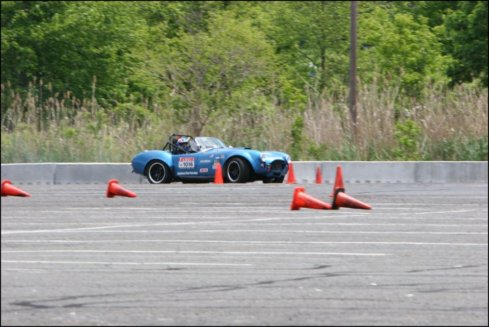 Blue convertible sports car with racing decals on a track, navigating orange cones