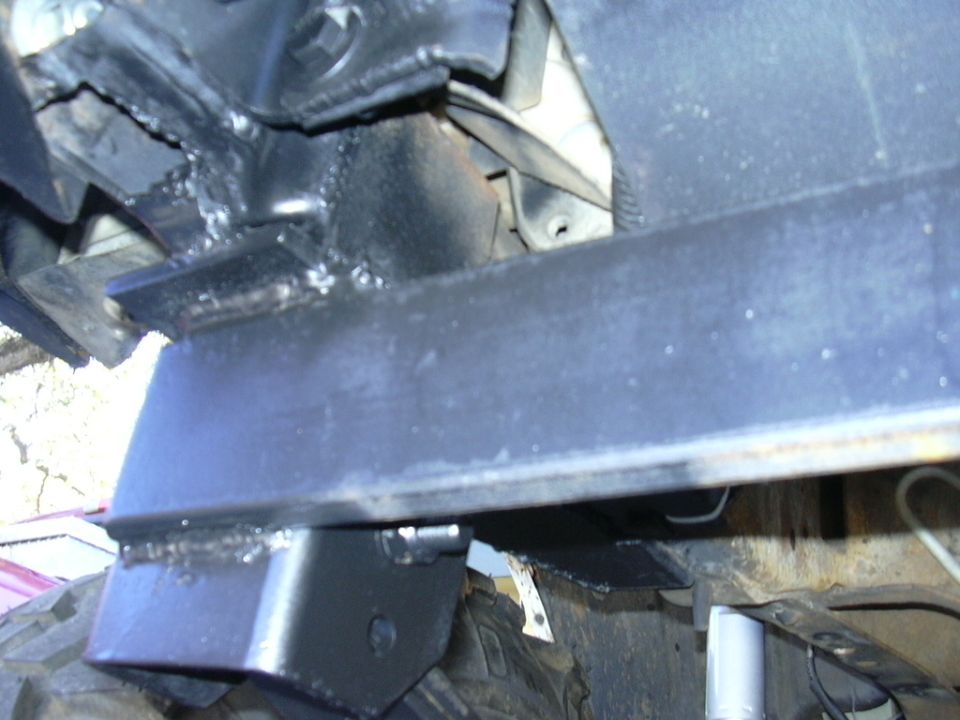 Close-up of welded metal brackets on a vehicle frame, possibly for a suspension modification