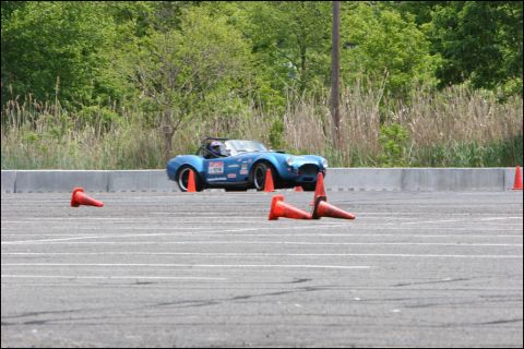 2001 Mercury Grand Marquis - A blue convertible sports car with racing decals navigates an autocross course, marked by orange cones.