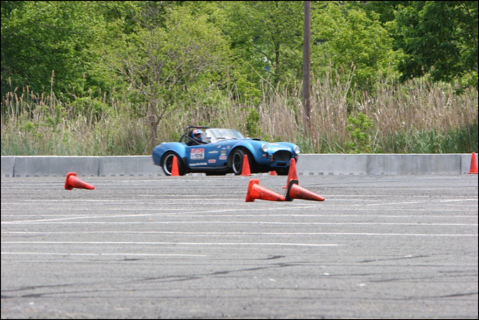 Blue convertible sports car navigating autocross course with orange cones