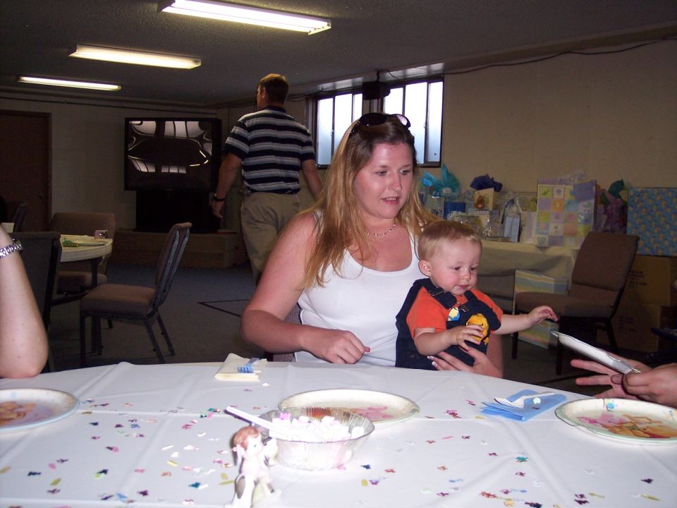 Woman holding a baby at a table covered with confetti. Another person's hand is visible on the right