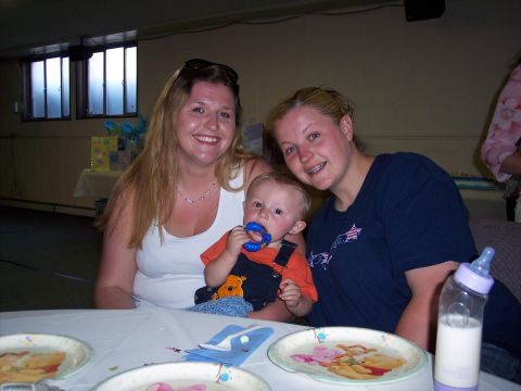 1972 Ford Ranchero - A baby is held by two women at a gathering, with plates and a baby bottle on the table.
