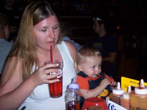 1972 Ford Ranchero - A woman and a baby are seated at a table, with the woman drinking from a cup and the baby eating.
