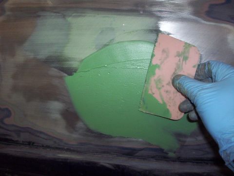 1998 Ford Crown Victoria - Body filler is being applied to a metal surface with a spreader.