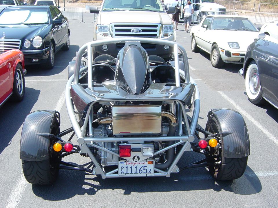 Rear-engine sports car with exposed engine and roll cage, California license plate 11165