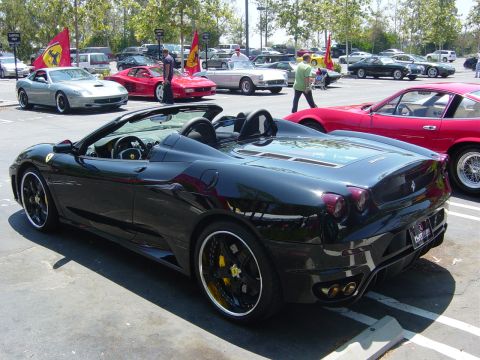 1993 Ford Probe - A black convertible sports car is parked in a lot with other vehicles and flags.
