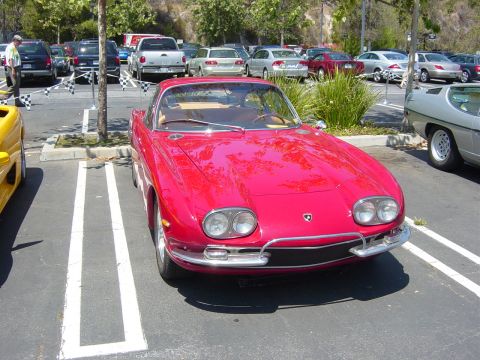 1993 Ford Probe - A red classic sports car is parked in a lot with other vehicles around it.
