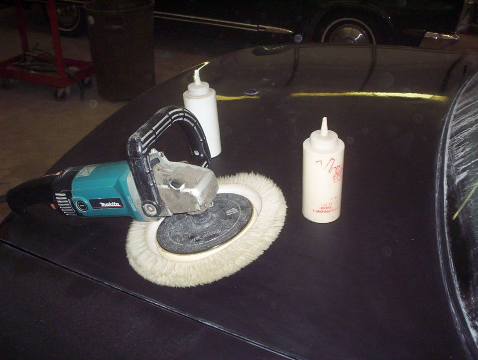 Polisher and two squeeze bottles on a dark car hood