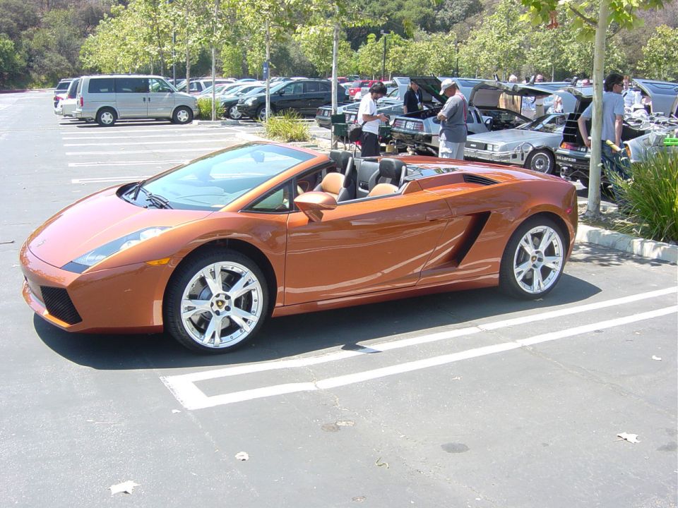 Orange convertible sports car parked in a lot with other vehicles