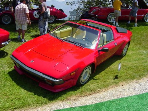 1993 Ford Probe - A red sports car is parked on grass at an outdoor event with other vehicles and people around.