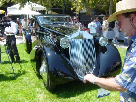 1993 Ford Probe - A man examines a classic black automobile with an ornate chrome grille at an outdoor event.