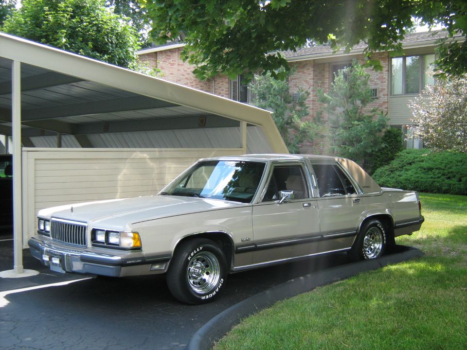 Tan 1988 Mercury Grand Marquis sedan parked on asphalt with a carport overhead