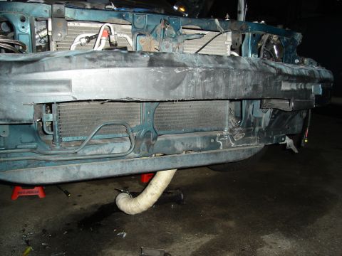 1995 Mazda MX-6 - The front of a car is shown with its bumper removed, revealing the radiator and other components, indicating damage or repair work.
