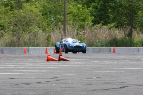 2001 Mercury Grand Marquis - A blue convertible sports car drives on a race track, marked by orange cones.