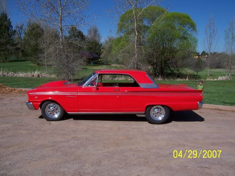 1994 Ford Bronco - Side view of a red 1963 Ford Falcon with a hood scoop and aftermarket wheels.