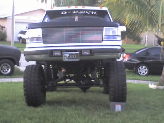 Lifted white Ford Bronco front view on a lawn with billet grille and large mud tires