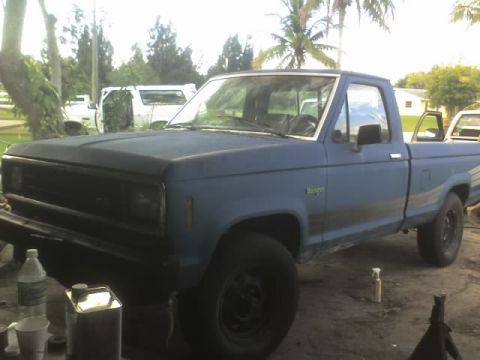 1995 Ford Bronco - A blue pickup truck is parked outside with other vehicles in the background.