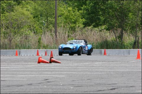 2001 Mercury Grand Marquis - A blue convertible sports car is seen on a race track during an event, with orange cones marking the course.