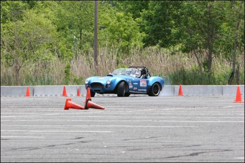 2001 Mercury Grand Marquis - A blue AC Cobra replica navigates an autocross course, kicking up dust as it turns.