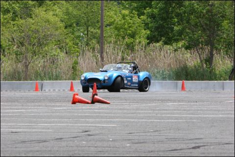 2001 Mercury Grand Marquis - A blue convertible sports car navigates an autocross course, kicking up dust.