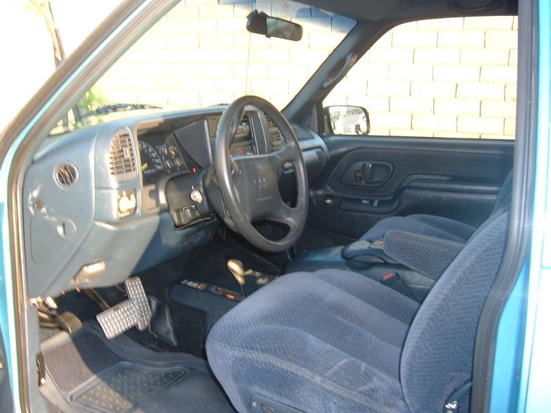 Blue truck interior with cloth seats, dashboard, steering wheel, and floor pedals