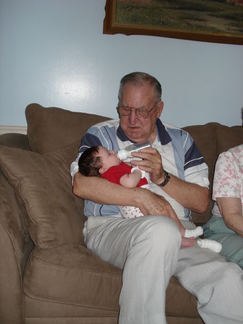 2000 Ford Crown Victoria - Grandfather feeding his grandchild from a bottle while sitting on the couch.