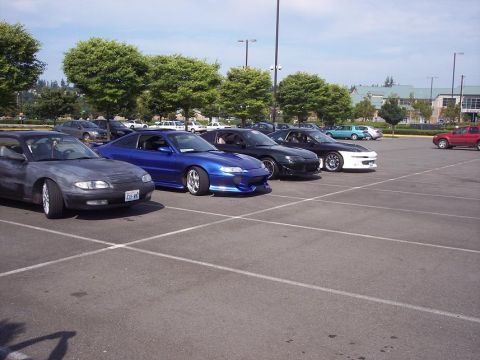 1995 Ford Probe - A line of sports cars, including a 1995 Ford Probe, are parked in a lot on a sunny day.