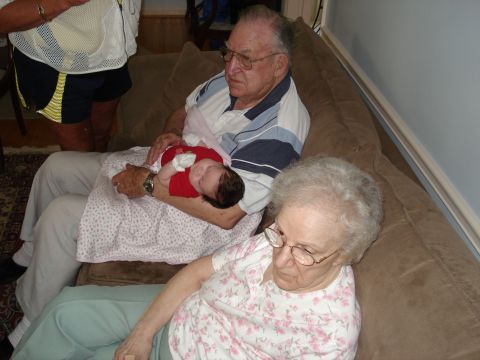 2000 Ford Crown Victoria - A family gathering with grandparents holding a baby on a couch.
