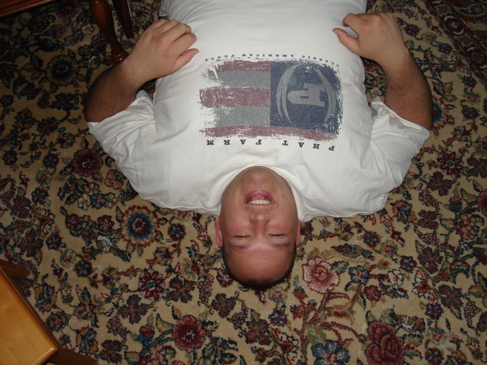 Man lying on a floral carpet, wearing a white t-shirt with an American flag graphic