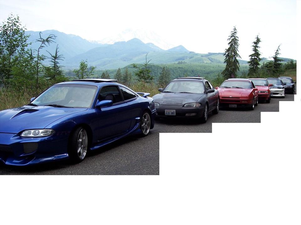 Blue coupe with a spoiler and body kit, parked in a line with other cars
