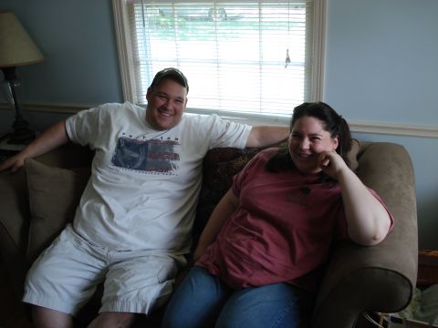 2000 Ford Crown Victoria - A couple relaxes on a couch in front of a window with blinds.