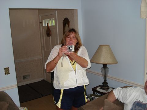 2000 Ford Crown Victoria - A woman stands indoors holding a digital camera, with a lamp and doorway visible in the background.