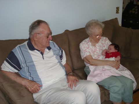 2000 Ford Crown Victoria - A family enjoys a visit together, with grandparents holding a young baby on a couch.